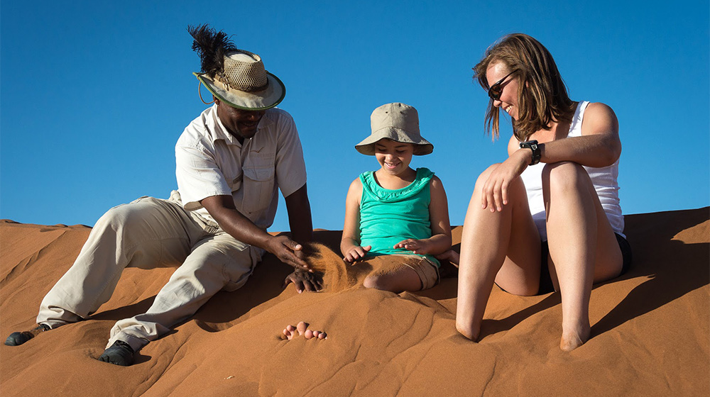 Local guide with mother and daughter on sand dunes in Namib dessert