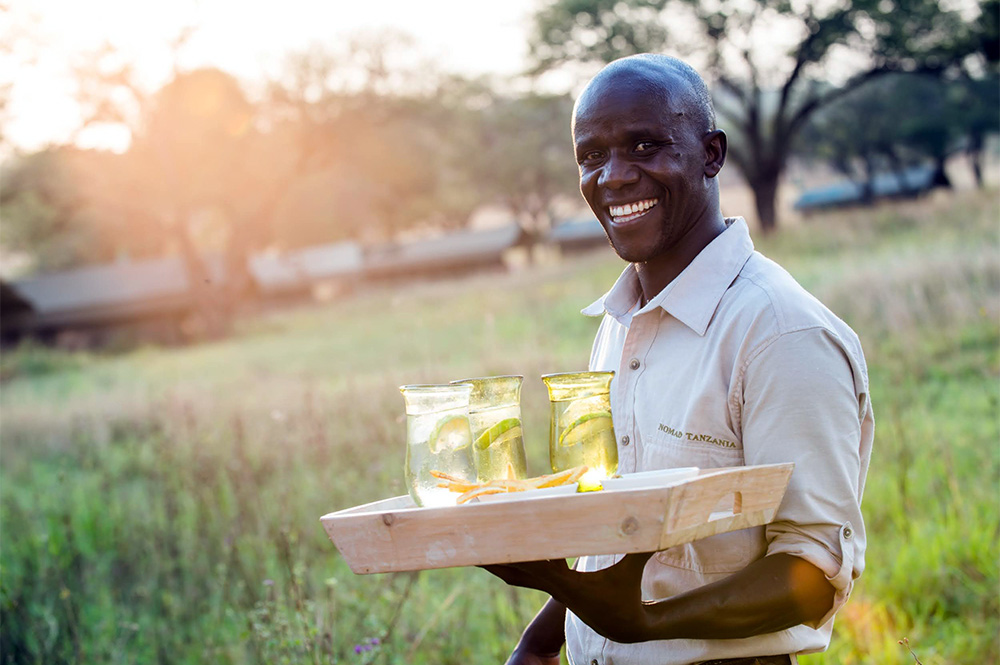 African man carrying drinks in Serengeti safari camp