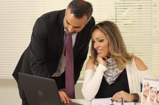 Man and woman office workers look at a laptop